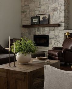 a living room filled with furniture and a fire place in front of a stone wall