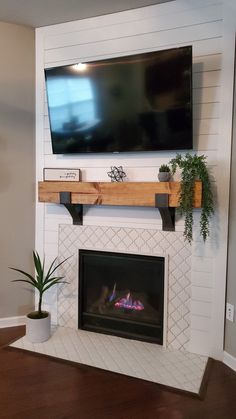 a fireplace with a flat screen tv mounted above it and a potted plant on the mantel