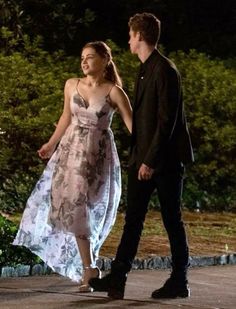 a young man and woman are walking down the street at night, dressed in evening gowns