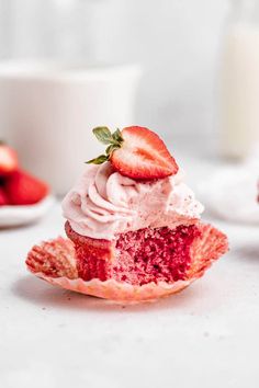 a strawberry cupcake with whipped cream and fresh strawberries on the side, ready to be eaten