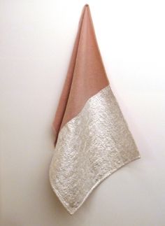 a white wall with a pink and silver towel hanging from it's side on the wall