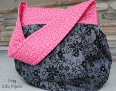 a black and pink purse sitting on top of a cement floor next to a brick wall