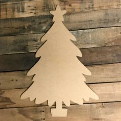 a wooden cutout of a christmas tree hanging on a wall with wood planks in the background