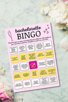 a pink and yellow bachelor party game on a marble table with flowers in the background