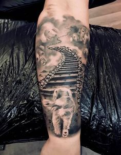 a man with a tattoo on his arm has a stairway leading up to the sky