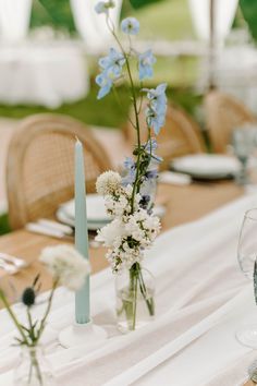 the table is set with blue and white flowers in glass vases on top of each other