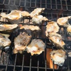 oysters being cooked on the grill with tongs