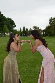 two women in long dresses touching noses with each other