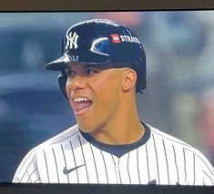 a baseball player wearing a new york yankees uniform and smiling in front of the camera