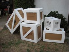 four cardboard boxes stacked on top of each other in front of a house with bushes