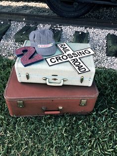 two suitcases are sitting on the grass with hats and other items in front of them