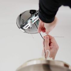 a person is holding the wires in their hand and pulling them apart from the ceiling