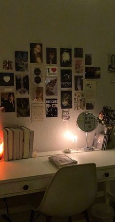 a white desk topped with a lamp next to a book and some pictures on the wall