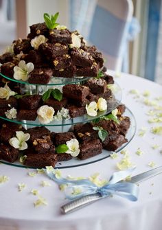 a three tiered cake with white flowers on the top and blue ribbon around it