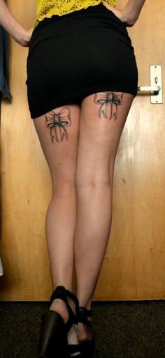 a woman with tattoos on her legs standing in front of a door