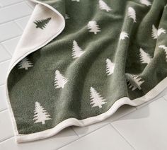 a green and white towel with trees on it sitting on top of a tiled floor