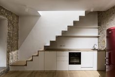 an empty kitchen with stairs leading up to the upper floor, and a red refrigerator