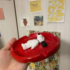 a hand is holding a red tray with a dog on it in the shape of a heart