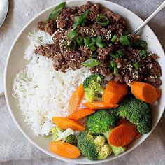 a white plate topped with rice, meat and veggies next to a spoon