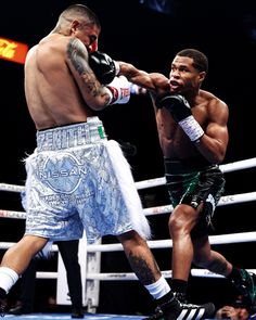 two men in the middle of a boxing match, one is punching the other with his hand