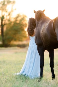 a woman in a white dress standing next to a brown horse