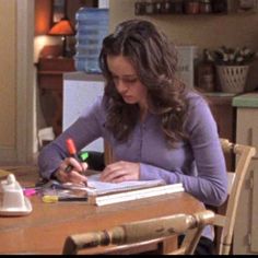 a woman sitting at a kitchen table writing