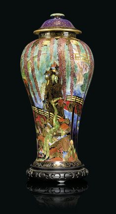 a colorful glass vase sitting on top of a black table next to a lamp shade