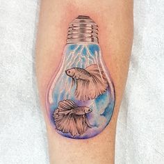 a tattoo on the leg of a person with a light bulb and two fish