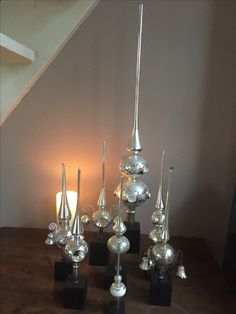 a group of silver vases sitting on top of a wooden table next to a candle