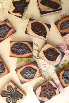 several small wooden coasters decorated with leaves and flowers on a white tablecloth background