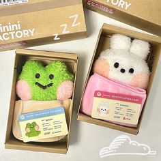 two small stuffed animals in boxes on a table