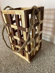 a bag made out of wood and rope sitting on the floor next to a wall