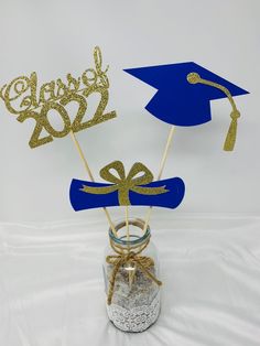 graduation decorations in a mason jar with blue and gold glitters on the top,