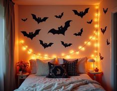 a bedroom decorated in halloween decorations with bats on the wall and fairy lights strung across the headboard