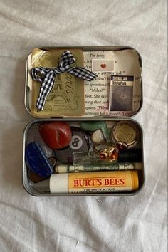 two tins filled with different types of items on top of a white sheet covered bed