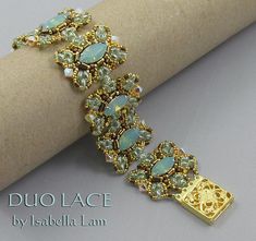 a gold bracelet with green and white stones sits on top of a roll of paper