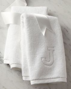 two white towels with the monogrammed j on them are sitting on a marble surface