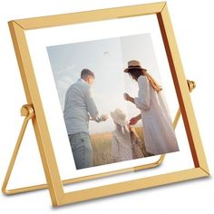 two people standing in front of a gold frame with an image of them holding hands