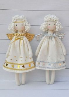 two white dolls with blonde hair are standing next to each other on a wooden wall