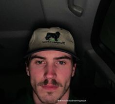 a man with a dog hat sitting in the back seat of a car at night