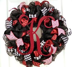 a black and red wreath with the letter k on it's front door hanger