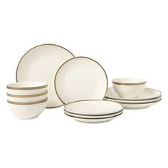 a set of white and gold dinnerware with stripes on the side, including plates