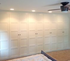 a bedroom with white closets and a ceiling fan in the middle of the room