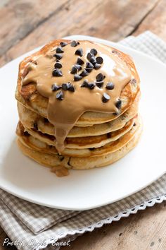 a stack of pancakes covered in chocolate chips and drizzled with peanut butter