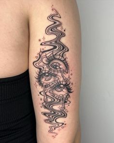 a woman's arm with a black and white tattoo design on the left shoulder