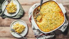 a casserole dish with corn and cheese on it, next to two plates