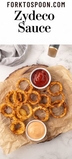 some onion rings are on a plate with ketchup and sauces next to it