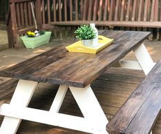 a wooden table with two benches and a potted plant sitting on top of it