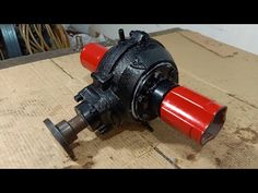 an old red and black pump sitting on top of a wooden table