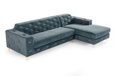 a blue velvet sectional sofa with gold studding on the arms and backrests